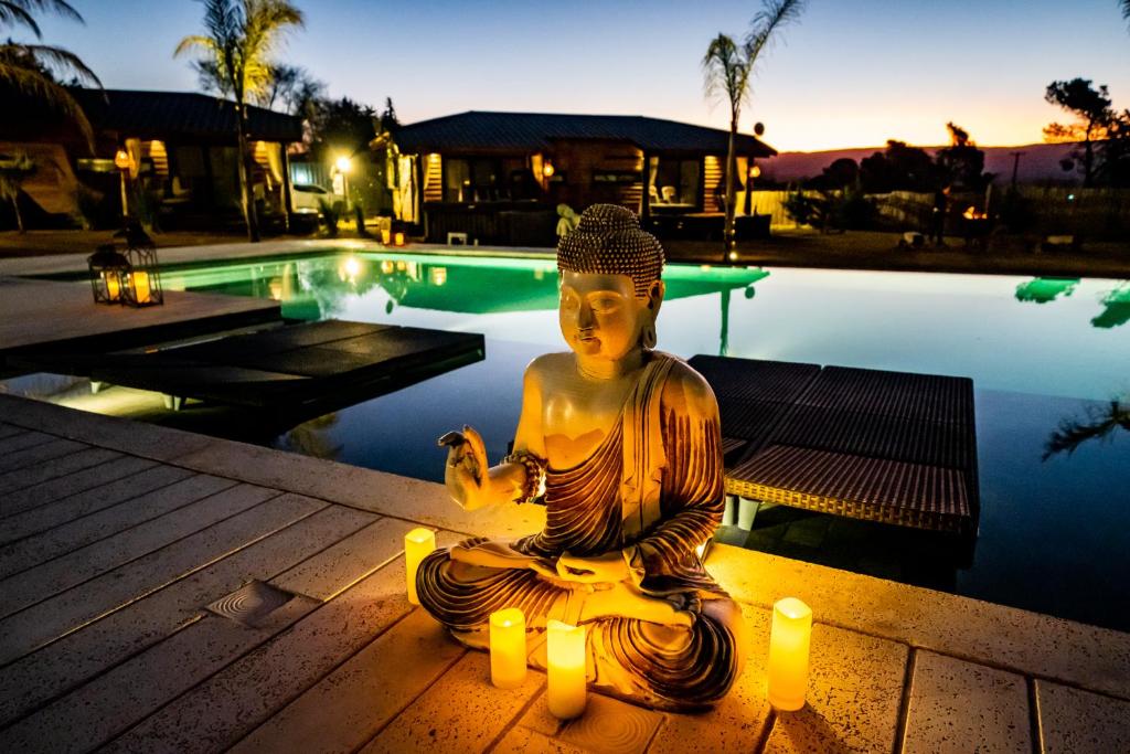 贝尔格拉诺将军镇OMM Suites Resort, Villa General Belgrano的游泳池旁有蜡烛的冥想女人的雕像