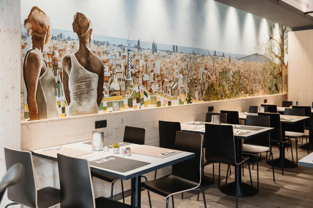 巴塞罗那塔拉维瑟拉酒店的一间带桌椅和大型壁画的餐厅