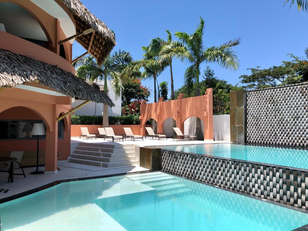 洛佩斯港New Nautilus Lodge的一座游泳池,位于一座带椅子和棕榈树的房子里