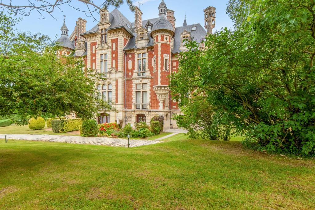 乌尔加特Appartement - Château de Beuzeval - Welkeys的一座大型红砖建筑,前面有树木