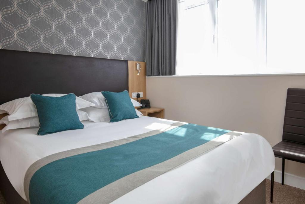 伦敦Best Western Northfields Ealing Hotel的一间卧室配有一张带蓝色枕头的大床