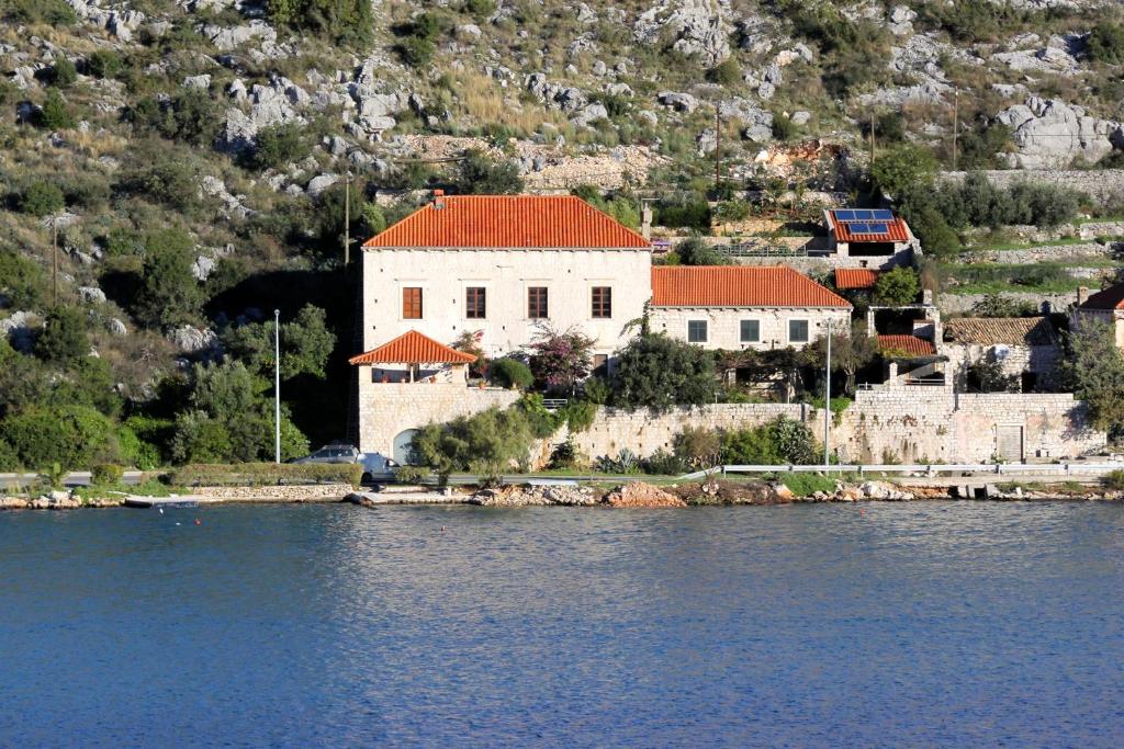 默克斯卡Seaside house with a swimming pool Mokosica, Dubrovnik - 8583的水边有红色屋顶的白色建筑