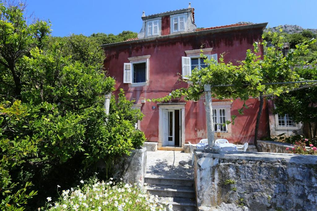 维甘Holiday house with a parking space Viganj - Podac, Peljesac - 10141的一座古老的红色房子,设有通往房子的楼梯