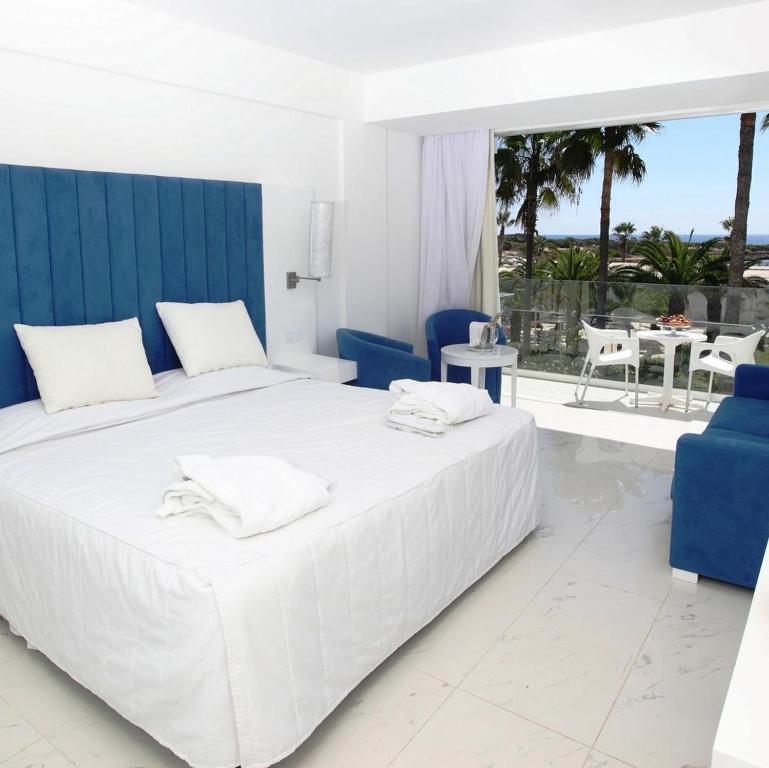 阿依纳帕Dome Beach Marina Hotel & Resort的白色卧室配有白色大床和蓝色椅子