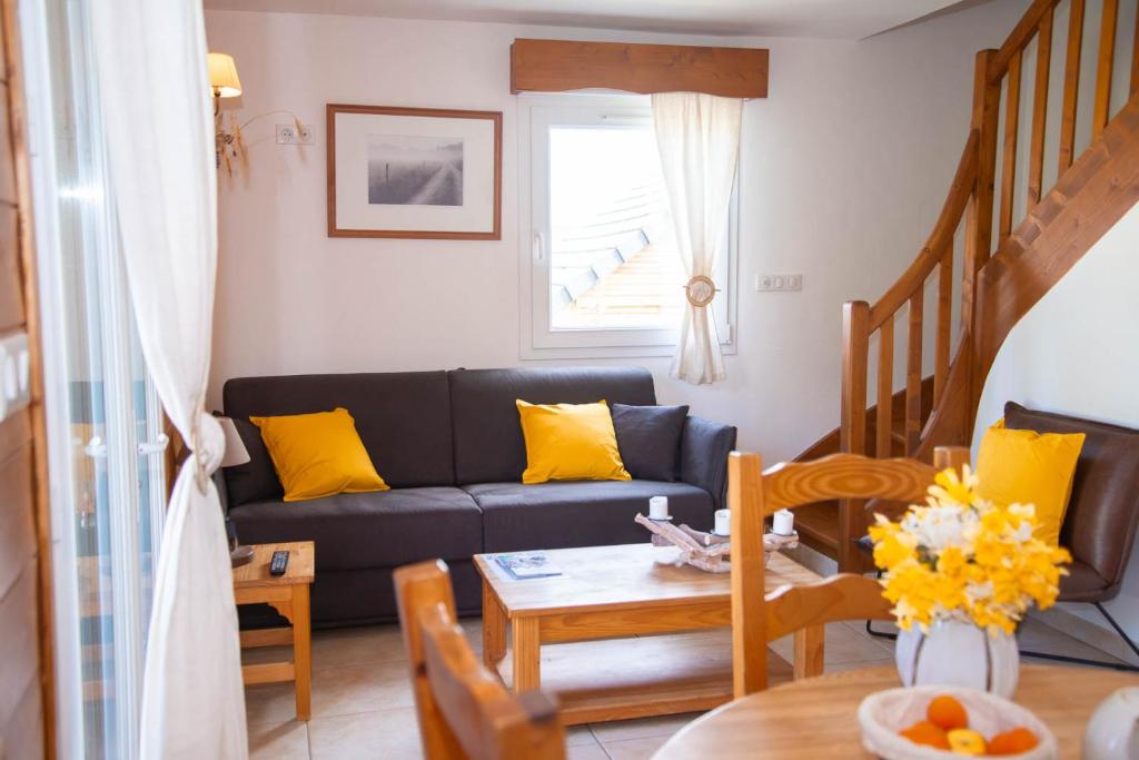 奥蒙奥布拉克Village de gîtes Les Chalets de l'Aubrac的客厅配有黑色沙发和黄色枕头