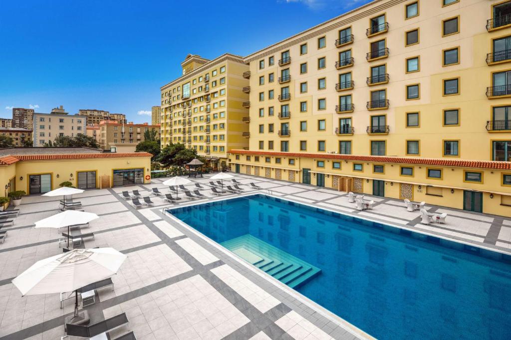 巴库巴库凯悦酒店的一座带椅子和遮阳伞的游泳池位于一座建筑旁边