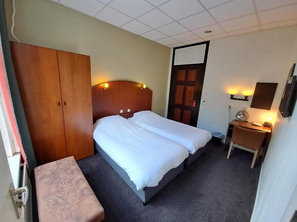 HoevenConferentiecentrum Hotel Bovendonk的卧室配有一张白色大床和一张书桌