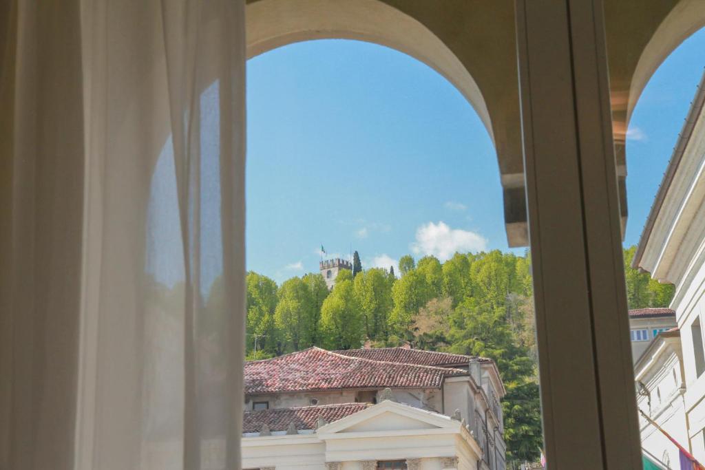 科内利亚诺Locanda Mezzosale的窗户享有建筑和树木的景致。