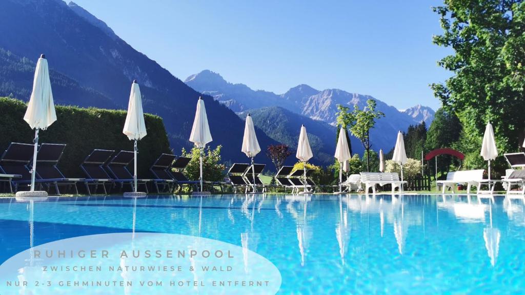 克雷纳尔Vital- & Familienhotel Angerwirt的一个带白色遮阳伞和山脉的游泳池