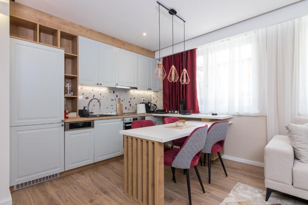 萨拉热窝Mayisa Apartments的厨房配有白色橱柜和桌椅