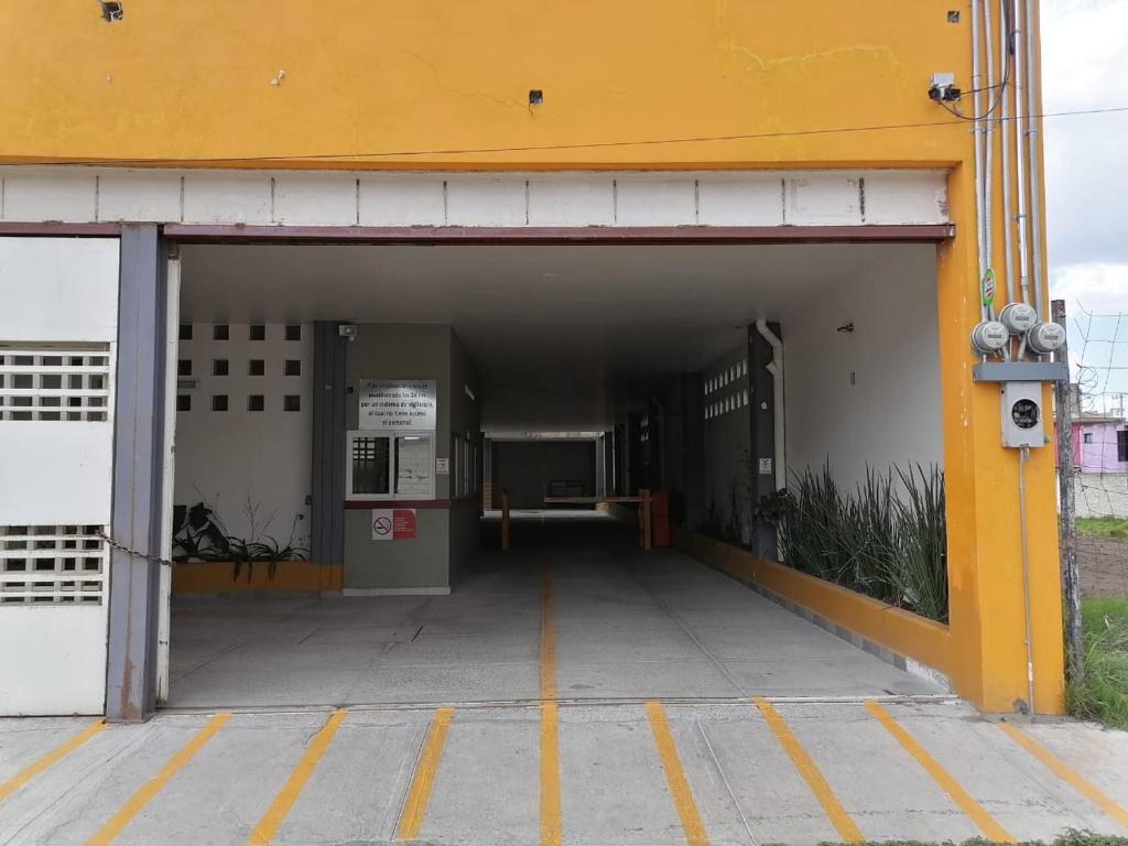 托卢卡Hotel Santino的黄色建筑停车库入口