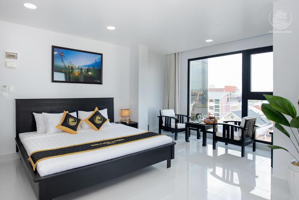 潘切Hoang Long Hotel Phan Thiết的一间卧室配有一张床和一张桌子及椅子