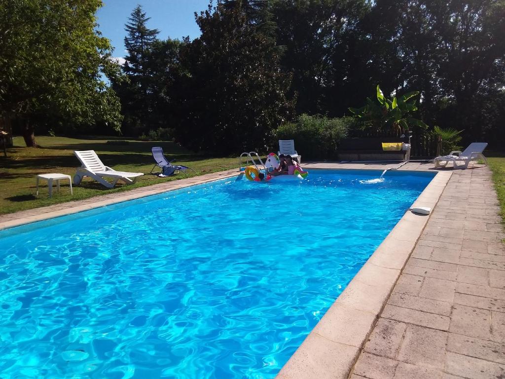 ViréPis-en-lits的一个大型蓝色游泳池,里面有人