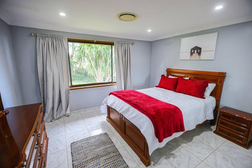 Mangrove MountainEntire House Beautiful Farm Stay 9 Bedrooms Sleeps 18 Enjoy Nature的一间卧室配有一张带红色枕头的床和一扇窗户