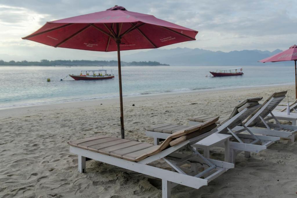吉利特拉旺安Warna Beach Hotel的海滩上的2把躺椅和1把遮阳伞