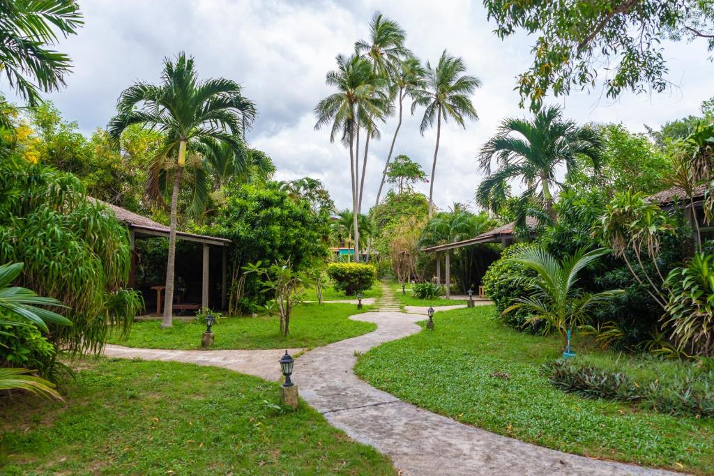 苏梅岛Satva Samui Yoga and Wellness Resort的一条穿过棕榈树花园的小路