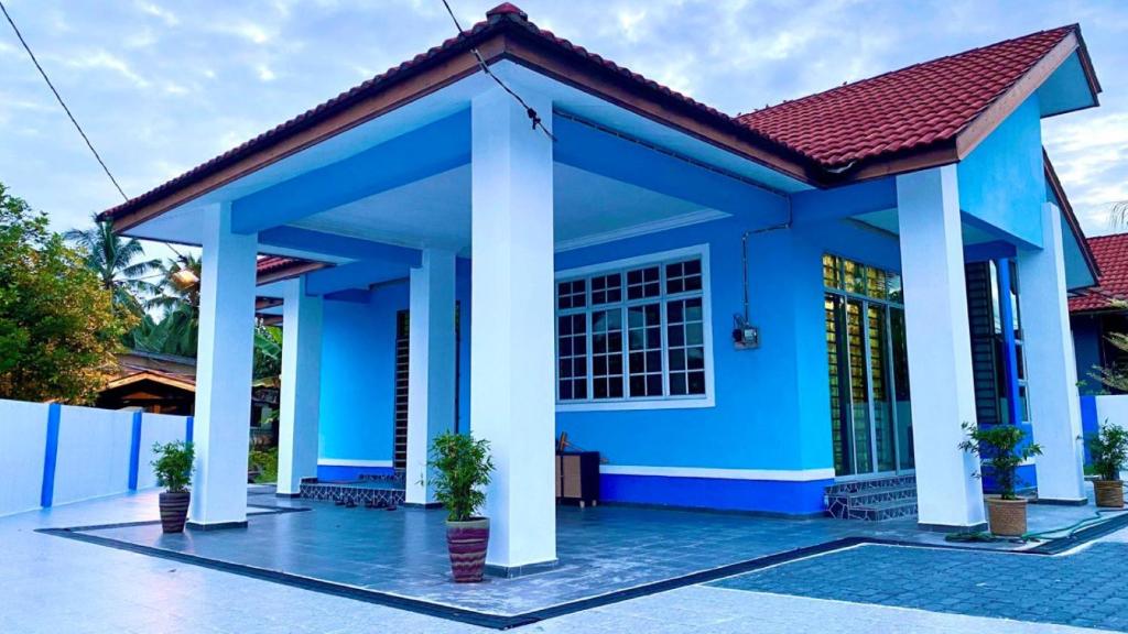 Kampong TamanSeri Idaman Guest House (Pasir Mas)的蓝色房子,有红色屋顶