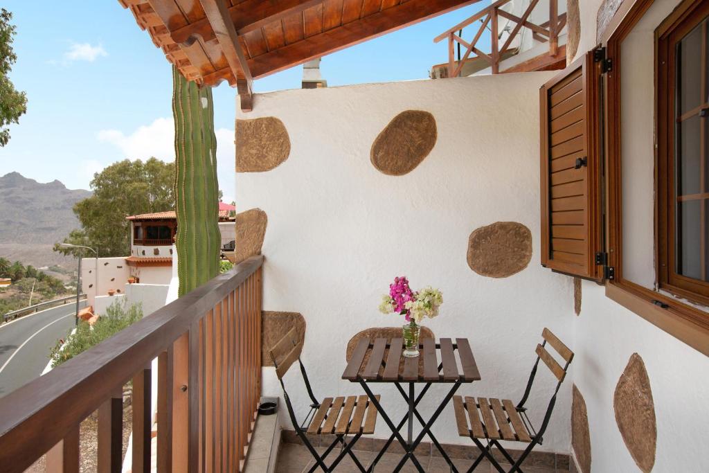 圣卢西亚Holiday Cottage Santa Lucía 2的阳台配有两把椅子和一张墙上的桌子
