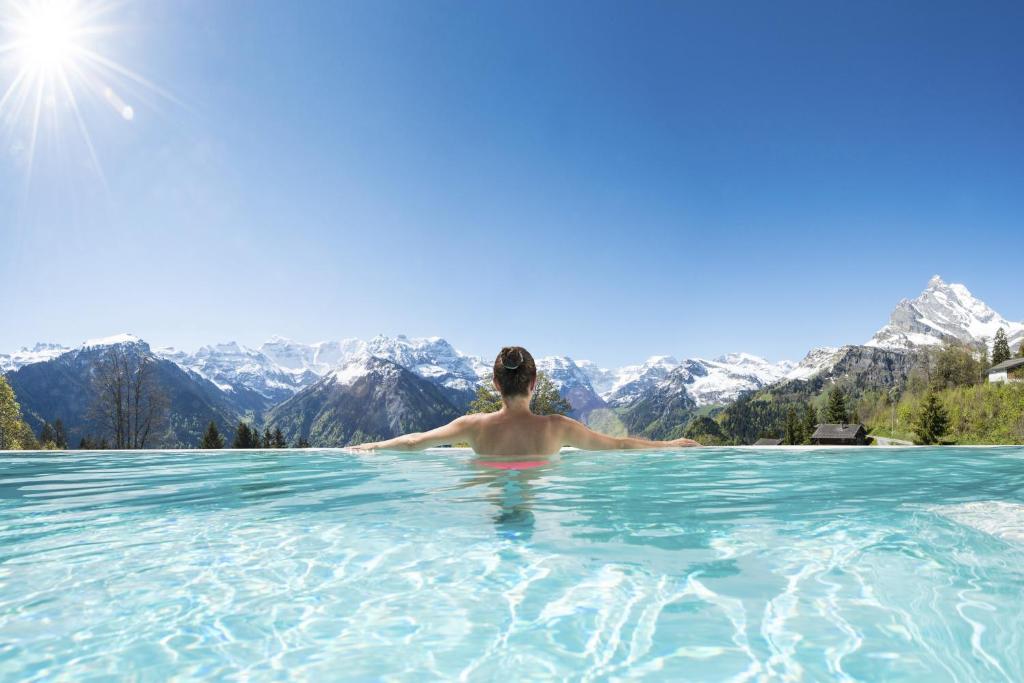 布劳瓦尔德Märchenhotel的背景为山脉的无边游泳池中的男人