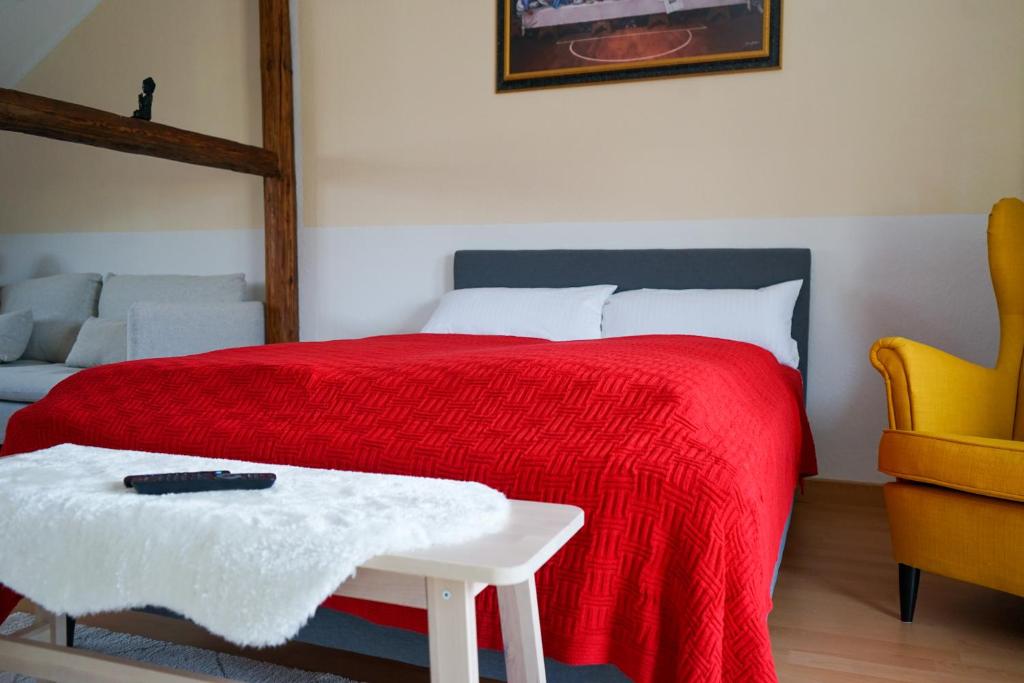 耶拿FULL HOUSE Premium Apartments Jena Holzmarkt的一间卧室配有一张带红色毯子和桌子的床。