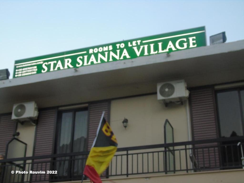 SiánaStar Sianna Village Rooms to let的前面有旗帜的建筑