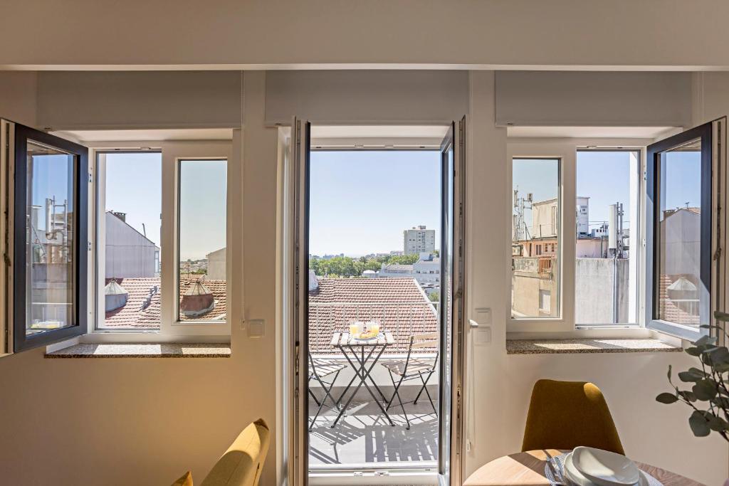 波尔图Urban House by LovelyStay的客房设有3扇窗户,享有城市美景。