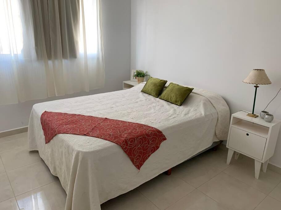 波萨达斯Alba II - Departamento 2 ambientes的白色卧室配有一张带绿色枕头的大床
