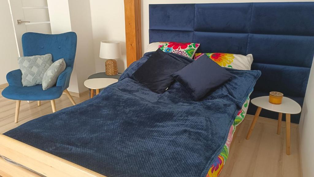 SzałszaKomfortowe Noclegi的一张带蓝色棉被和蓝色椅子的床