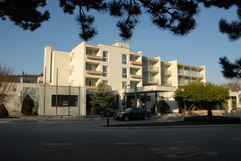 锡尼Rooms with a parking space Sinj, Zagora - 14466的前面有一辆汽车停放的白色建筑