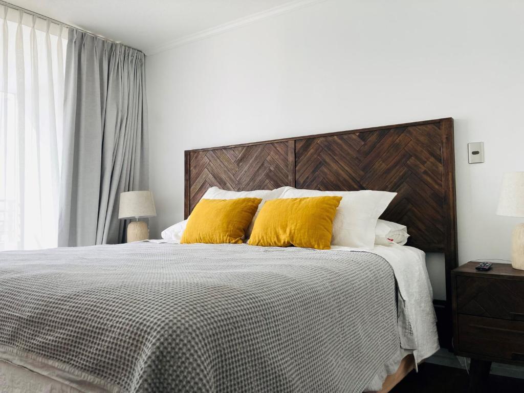 圣地亚哥Alta Vista Las Condes的一间卧室配有一张带两个黄色枕头的床
