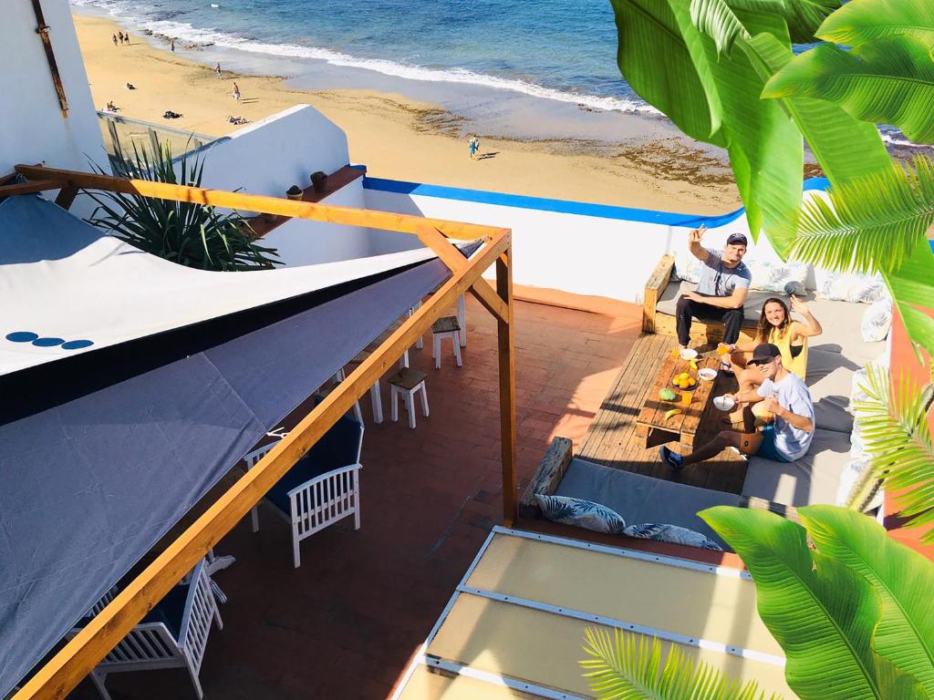 大加那利岛拉斯帕尔马斯Surf House Gran Canaria的一群人坐在海滩前的桌子旁