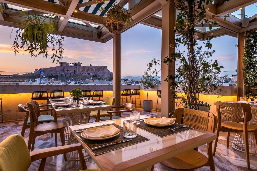 雅典Niche Hotel Athens的一间带桌椅的市景餐厅