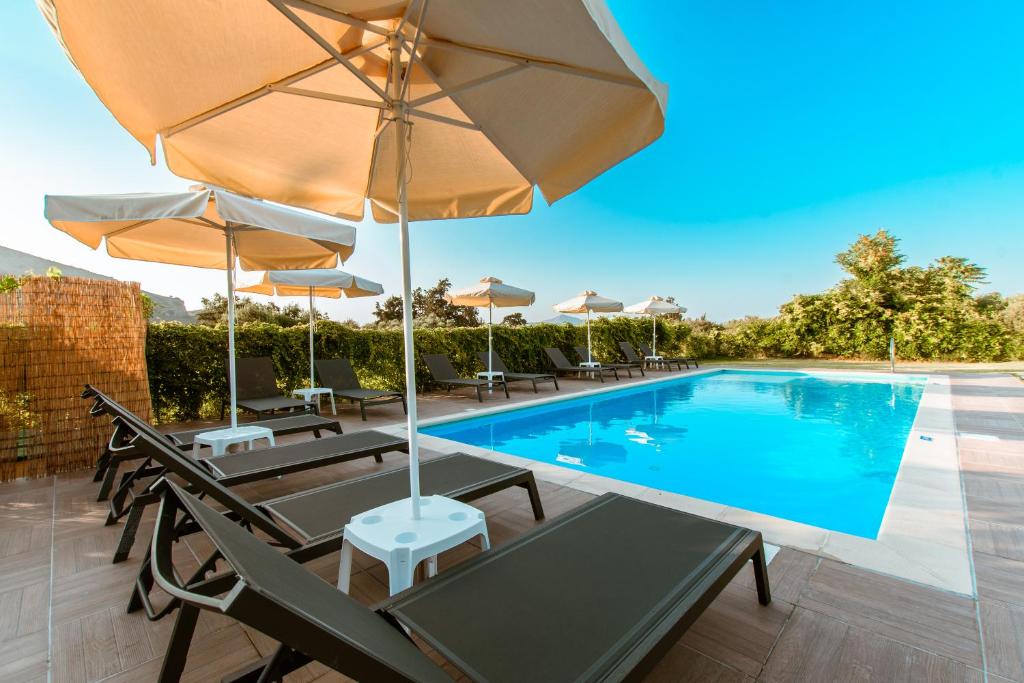 卡莱维斯Koulouris Apartments & Studios的一个带椅子和遮阳伞的游泳池和一个游泳池