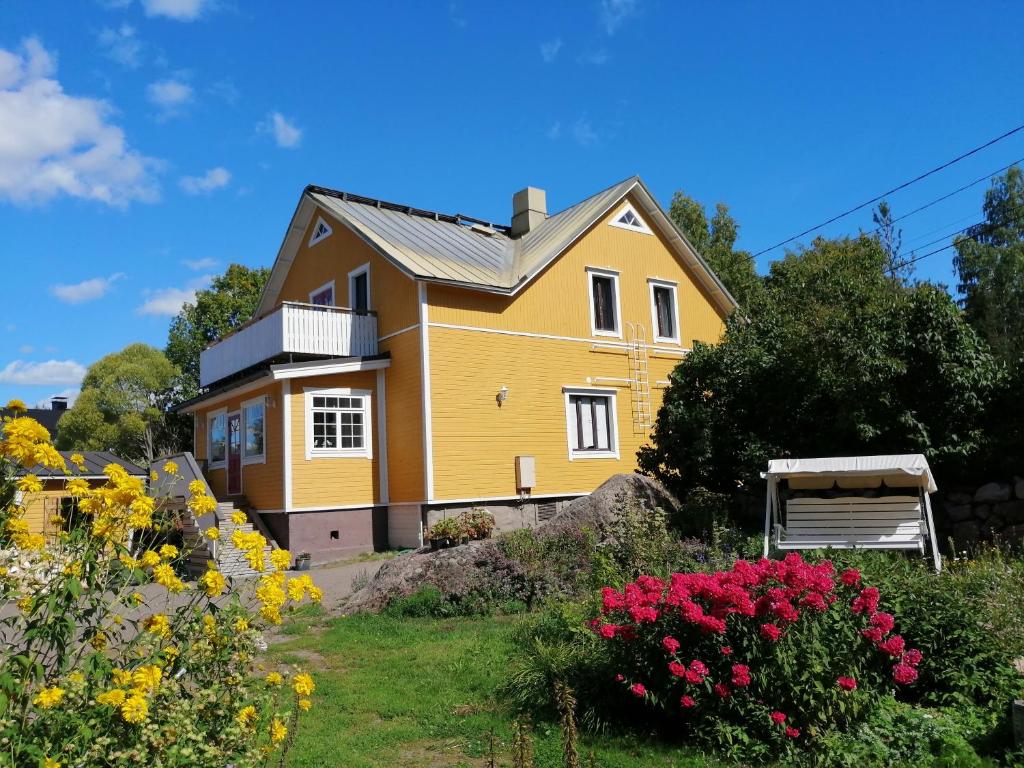 科特卡Guesthouse Lokinlaulu的院子里的黄色房子,鲜花盛开