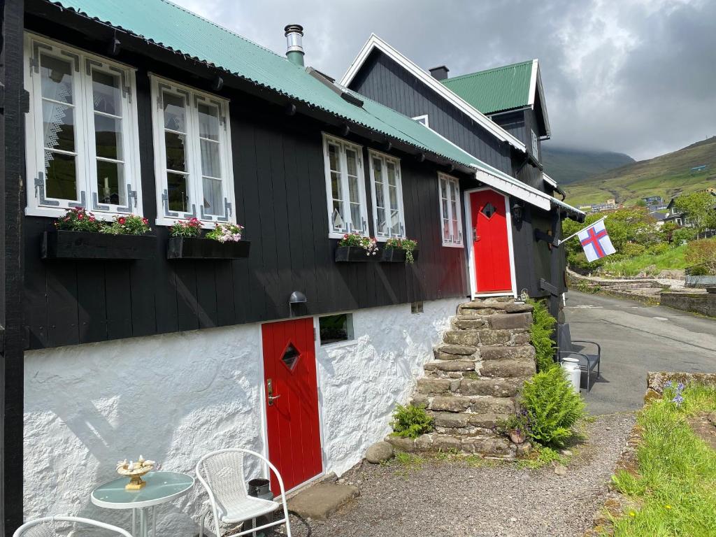 KvívíkCharming and Authentic Heritage Retreat in Kvívík - right next to the river的一间设有红色门和桌椅的房子