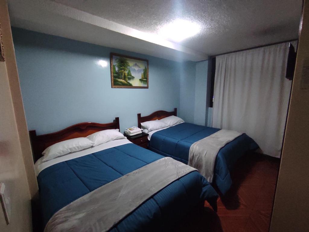 伊瓦拉Hostal Buenaventura Ibarra的蓝色墙壁客房的两张床