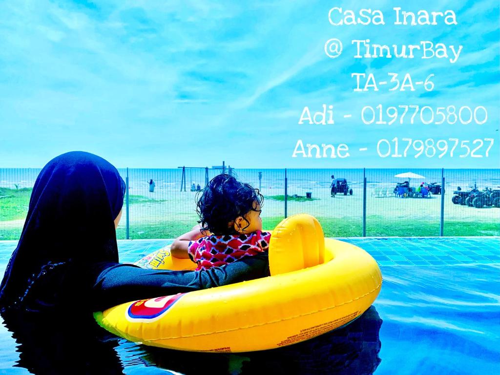 关丹TimurBay Seafront Residence at Casa Inara的把孩子放在排筏上的妇女