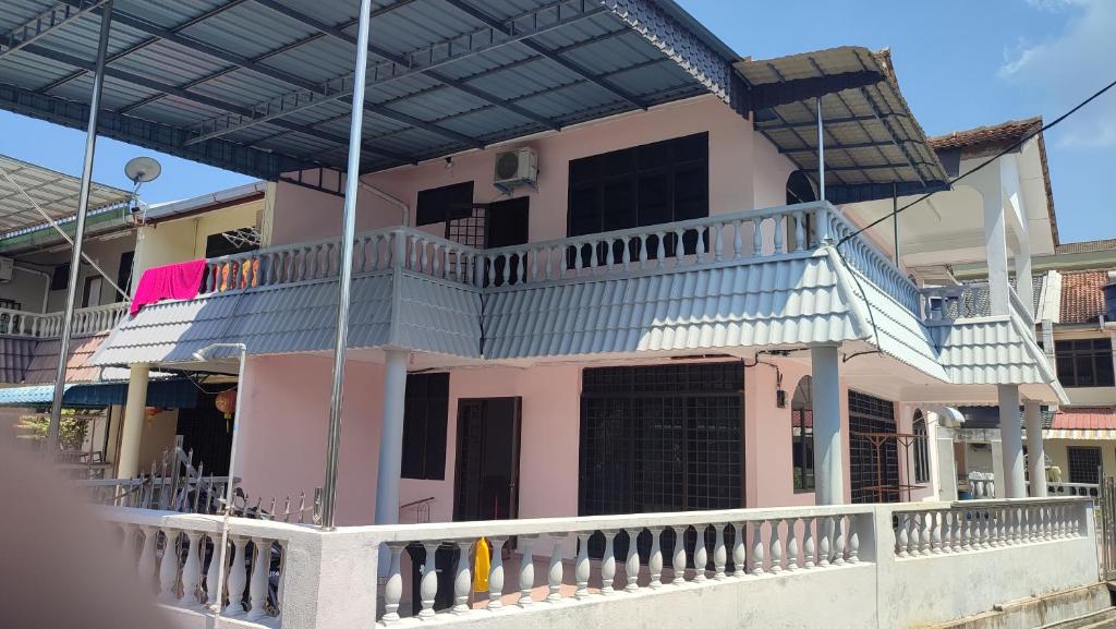 卡庞帕斯班伽克Pangkor Bogar Beach Homestay 邦咯岛民宿的粉红色的房子,设有带甲板的阳台
