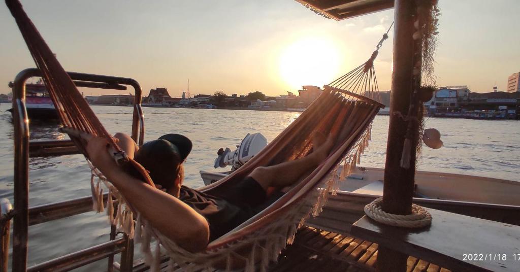 曼谷Sabai Sabai Liveaboard Bangkok的躺在船上吊床上的男人