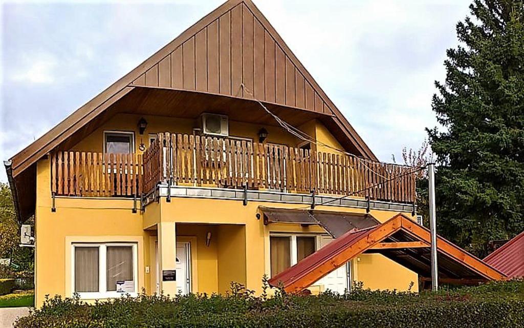 沃尼奥尔茨沃什海吉Balassa Családi Apartman的带阳台和楼梯的黄色房屋