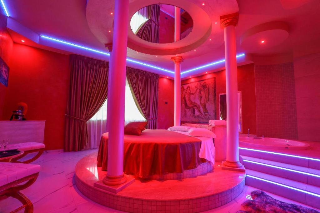 埃博利Alcova Suite&Relax的一间卧室配有一张床和一个紫色灯光浴缸