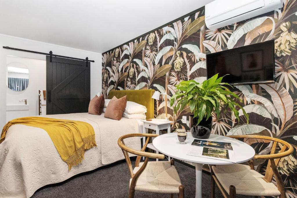 玛塔玛塔Matamata Lodge的一间卧室配有一张床和一张桌子及电视