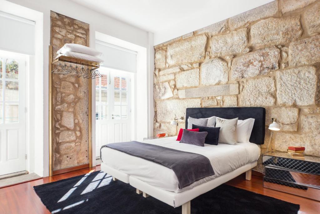 波尔图波尔图雅致舒适一室公寓酒店的一间卧室设有一张大床和石墙