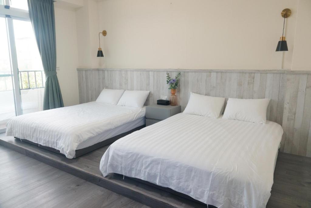 台东宿嘻民宿的卧室内的两张床,配有白色床单