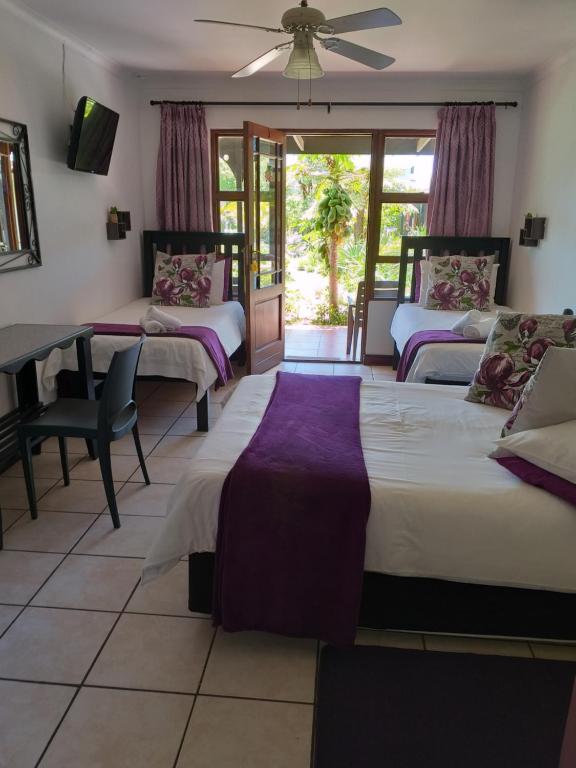 Molen Drift非洲之日旅馆的一间卧室配有三张床和一张桌子及椅子