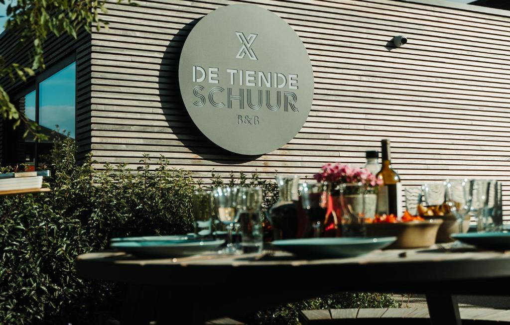 埃纲尔赫姆B&B De Tiendeschuur的大楼前的桌子,上面有盘子和酒杯