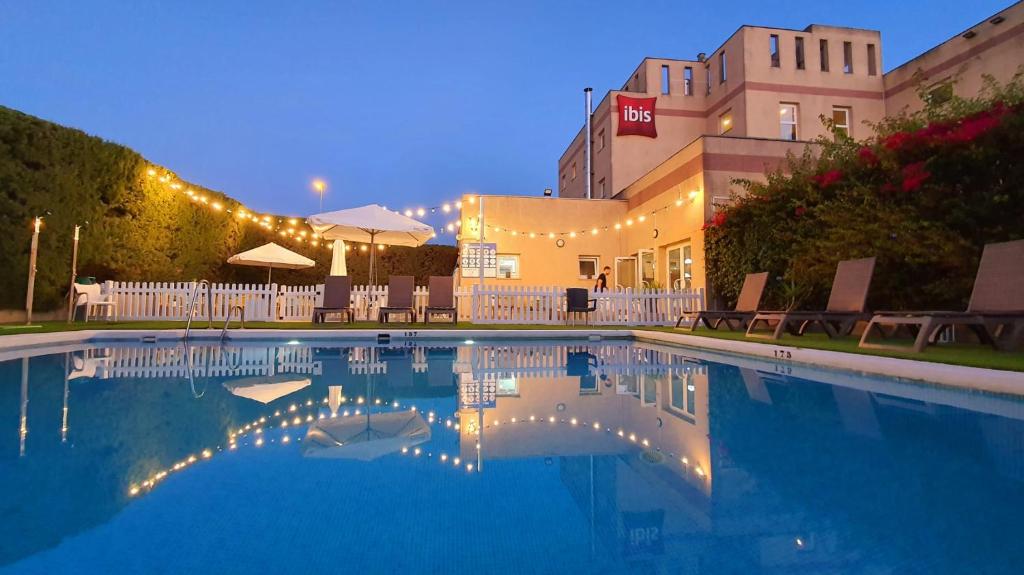 赫雷斯-德拉弗龙特拉赫雷斯德拉弗龙特拉加的斯宜必思酒店的大楼内的一个夜间游泳池,灯光照亮