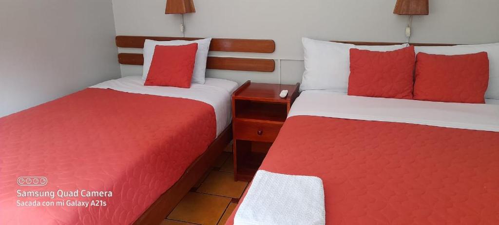 马丘比丘拉派查旅馆的两张位于酒店客房的床,配有红色和白色床单