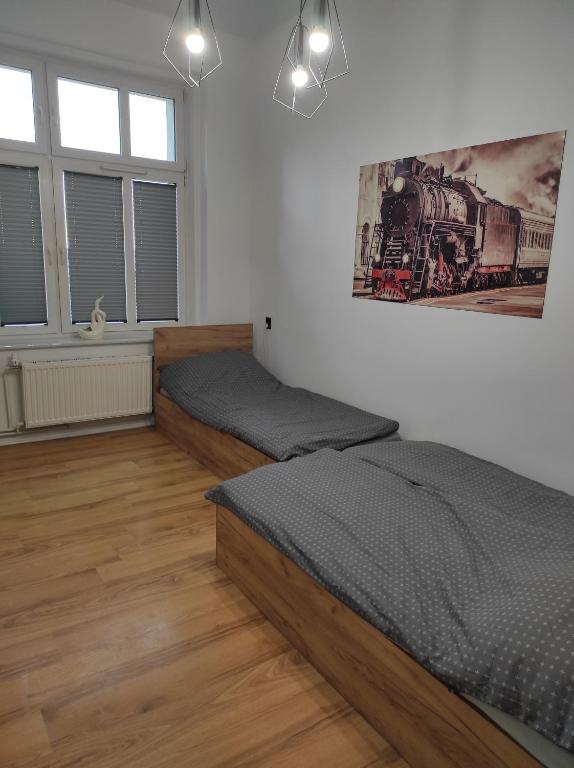霍伊尼采Apartament "Przy Dworcu"的一间卧室设有两张床,墙上挂着一幅画