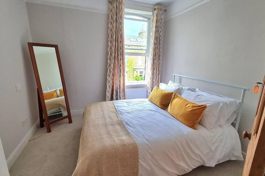 斯基普顿Brylie House, Large Central family home的一间卧室配有一张带黄色枕头和镜子的床